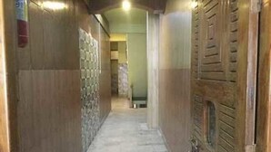 A hallway with a marble floor, wooden doors, and a wall with a patterned design. - Hotel Tashila - Manali (Manali)