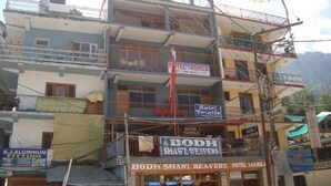A multi-story building with signs for 'Hotel Tashila' and 'Bodh Shawl Weavers Hotel'. - Hotel Tashila - Manali (Manali)