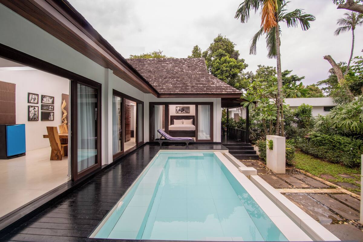 A modern house with a swimming pool, a lounge chair, and a staircase leading to a covered patio.