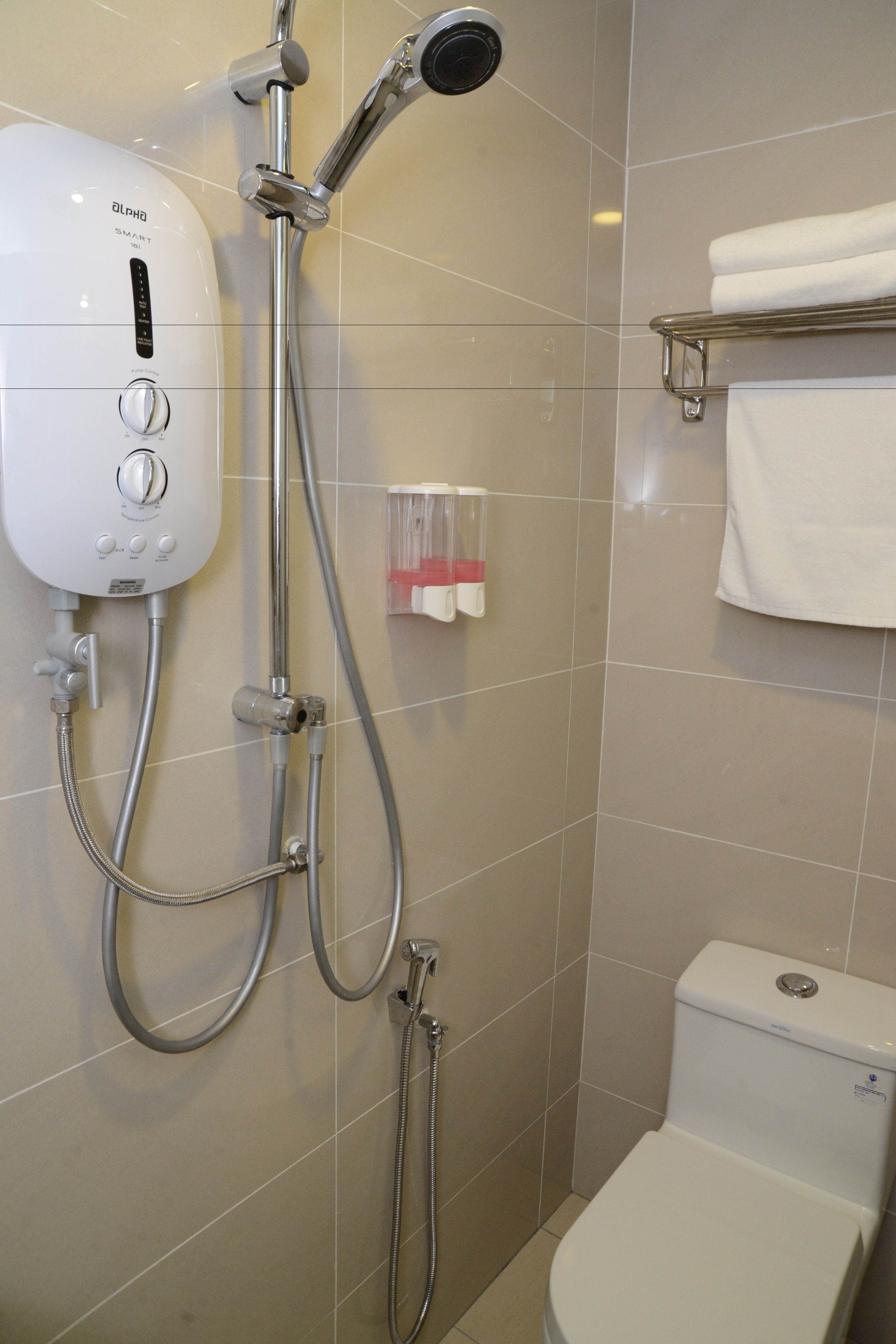 A bathroom with a modern shower system, a toilet, and a towel rack.