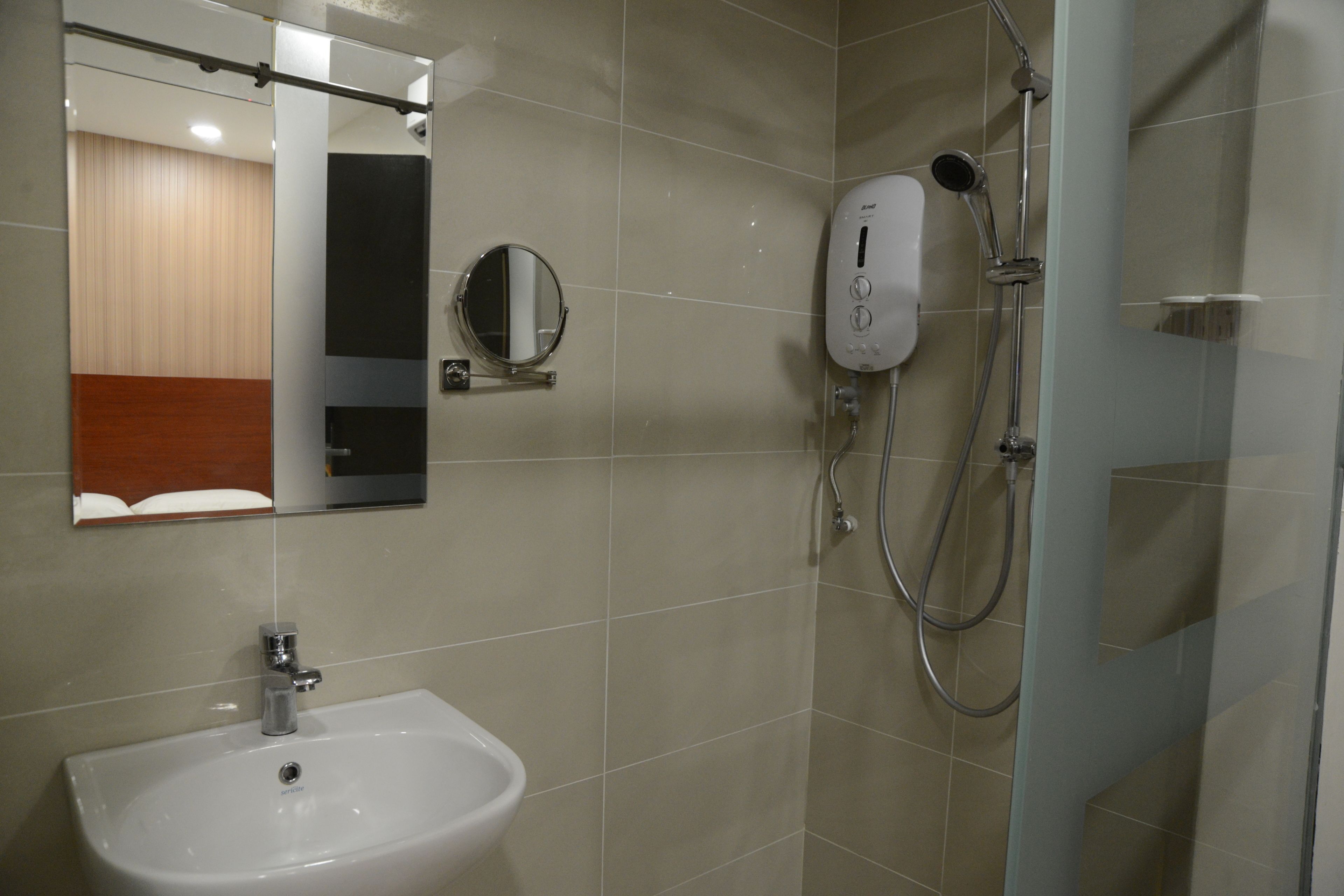 Une salle de bain équipée d’un lavabo, d’un miroir et d’une douchette à main.