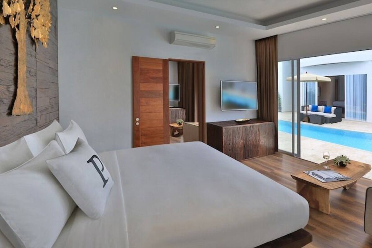 Une chambre d’hôtel moderne avec un grand lit, un canapé, une télévision et une vue sur la piscine.