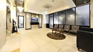 A modern hotel lobby with a reception desk, seating area, and large windows. - Masan Almond Hotel (Changwon)