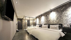 A modern hotel room with a large bed, a TV, and a herringbone-patterned wall. - Masan Almond Hotel (Changwon)