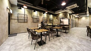 A modern conference room with wooden tables and chairs, a whiteboard, and a brick accent wall. - Masan Almond Hotel (Changwon)