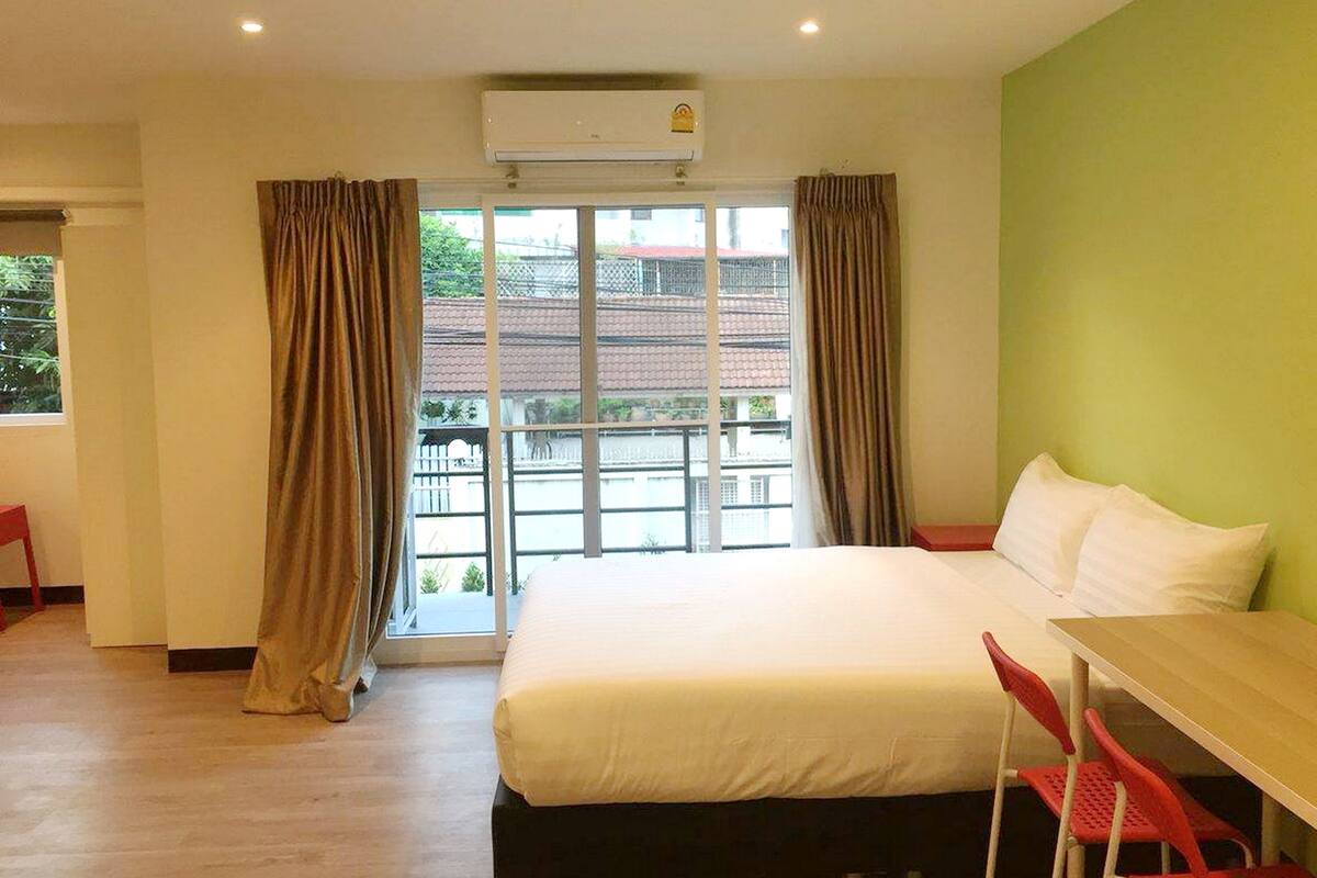 A hotel room with a bed, a desk, and a window with curtains.