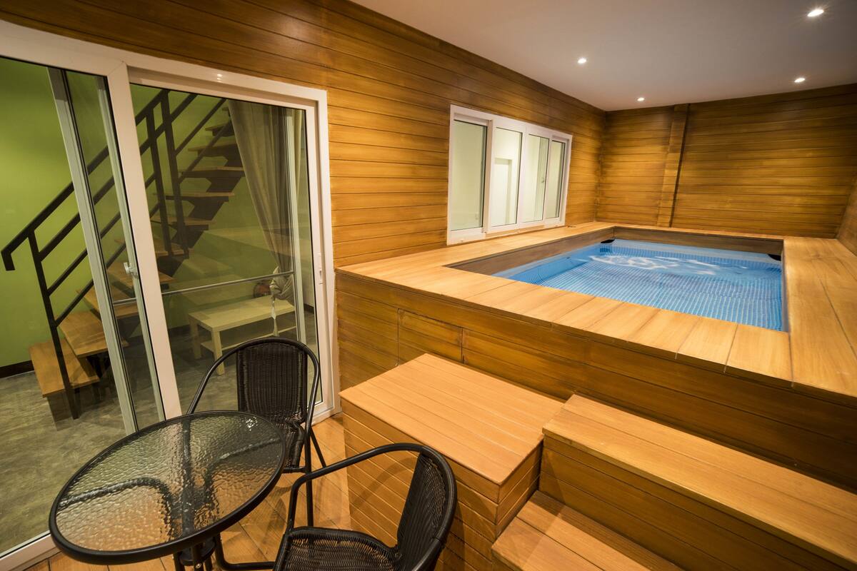 A wooden spa area with a hot tub, glass doors, and a staircase.