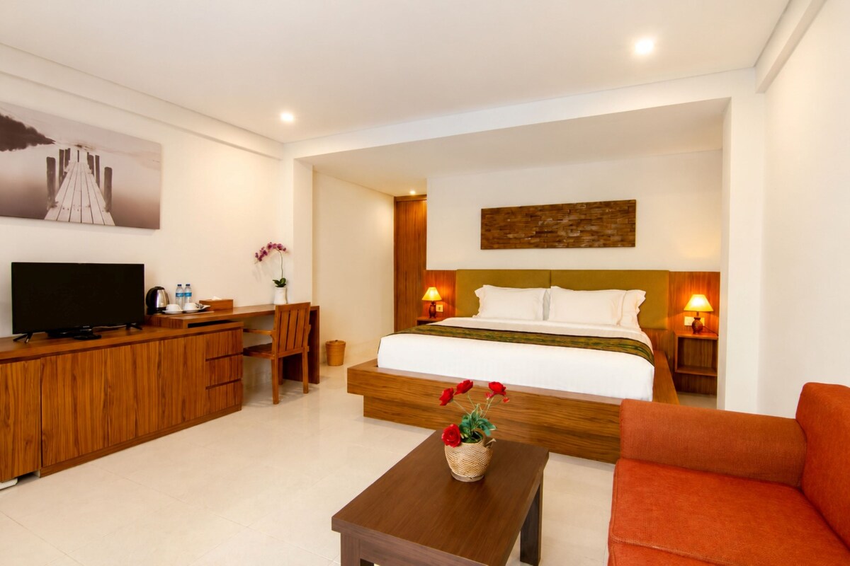 Quarto de hotel com cama, televisão, escrivaninha e cadeira.