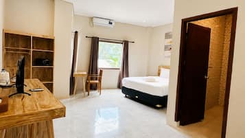 A hotel room with a bed, a desk, a chair, a wardrobe, and a window with curtains.