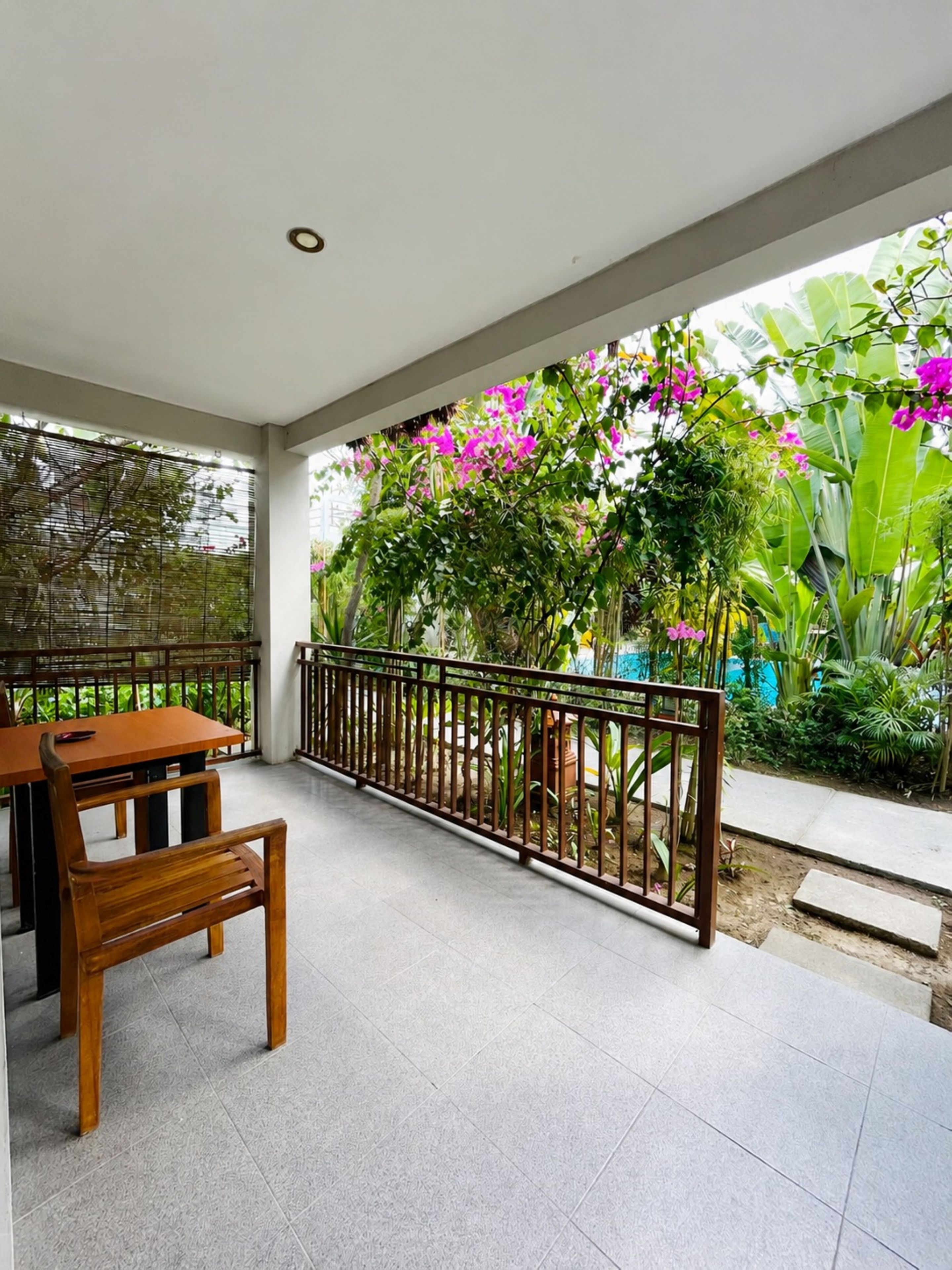 A covered patio area with a wooden table and bench, surrounded by a metal railing.
