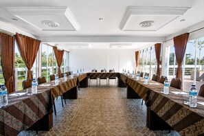 A conference room with a long table, chairs, water bottles, and a patterned floor. - Diva Lombok Resort (Senggigi)