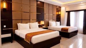 A hotel room with two beds, a large wall panel design, and a window with curtains.
