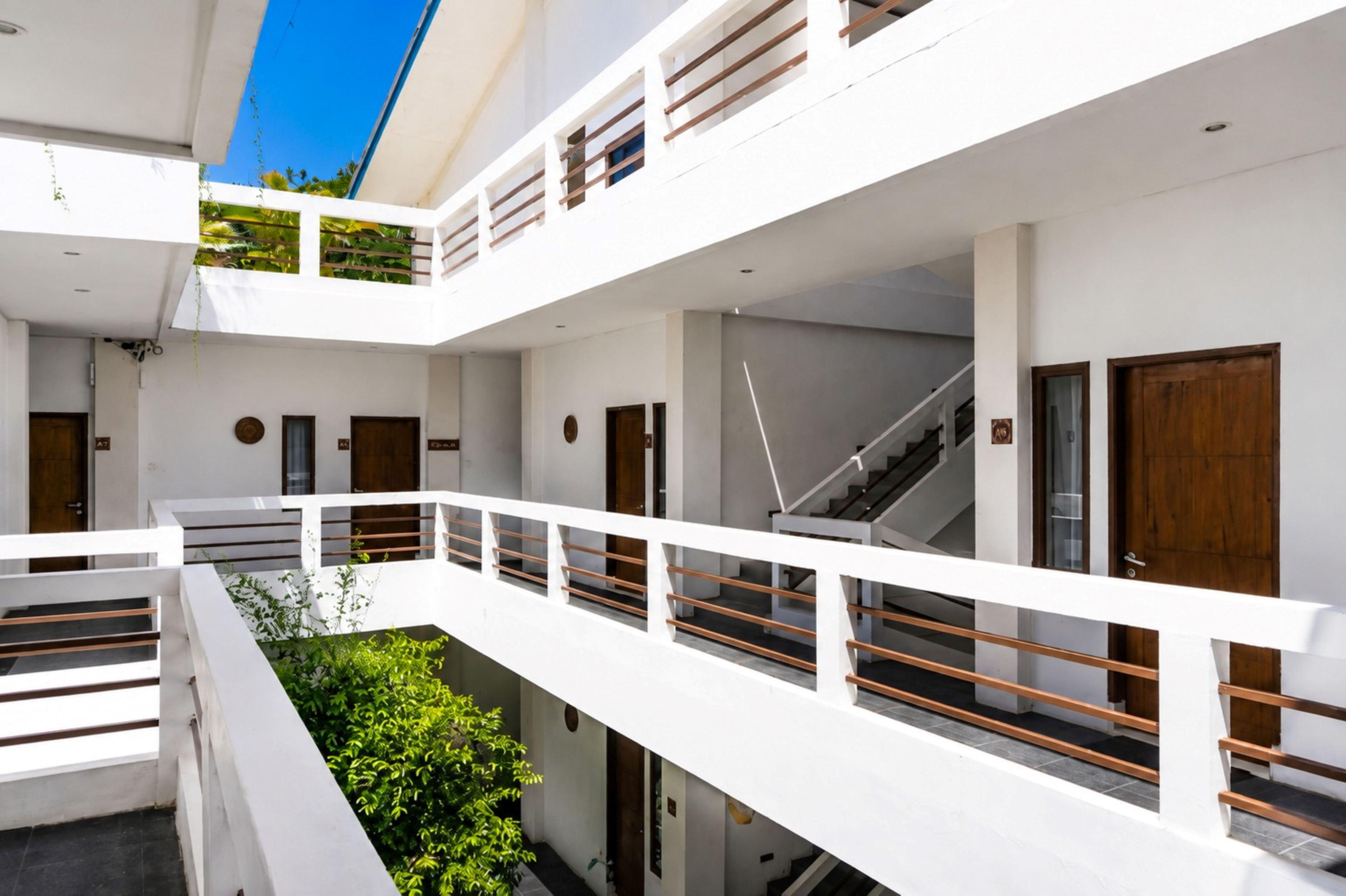A multi-level building with white exterior walls, a staircase, and a balcony with a railing.