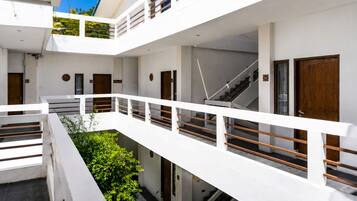 A multi-level building with white exterior walls, a staircase, and a balcony with a railing.