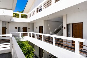 Edificio a più livelli con pareti esterne bianche, una scala e un balcone con ringhiera.