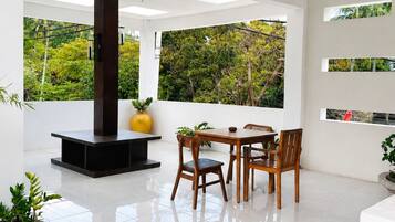 A modern interior with a dining area, a fireplace, and a view of greenery.