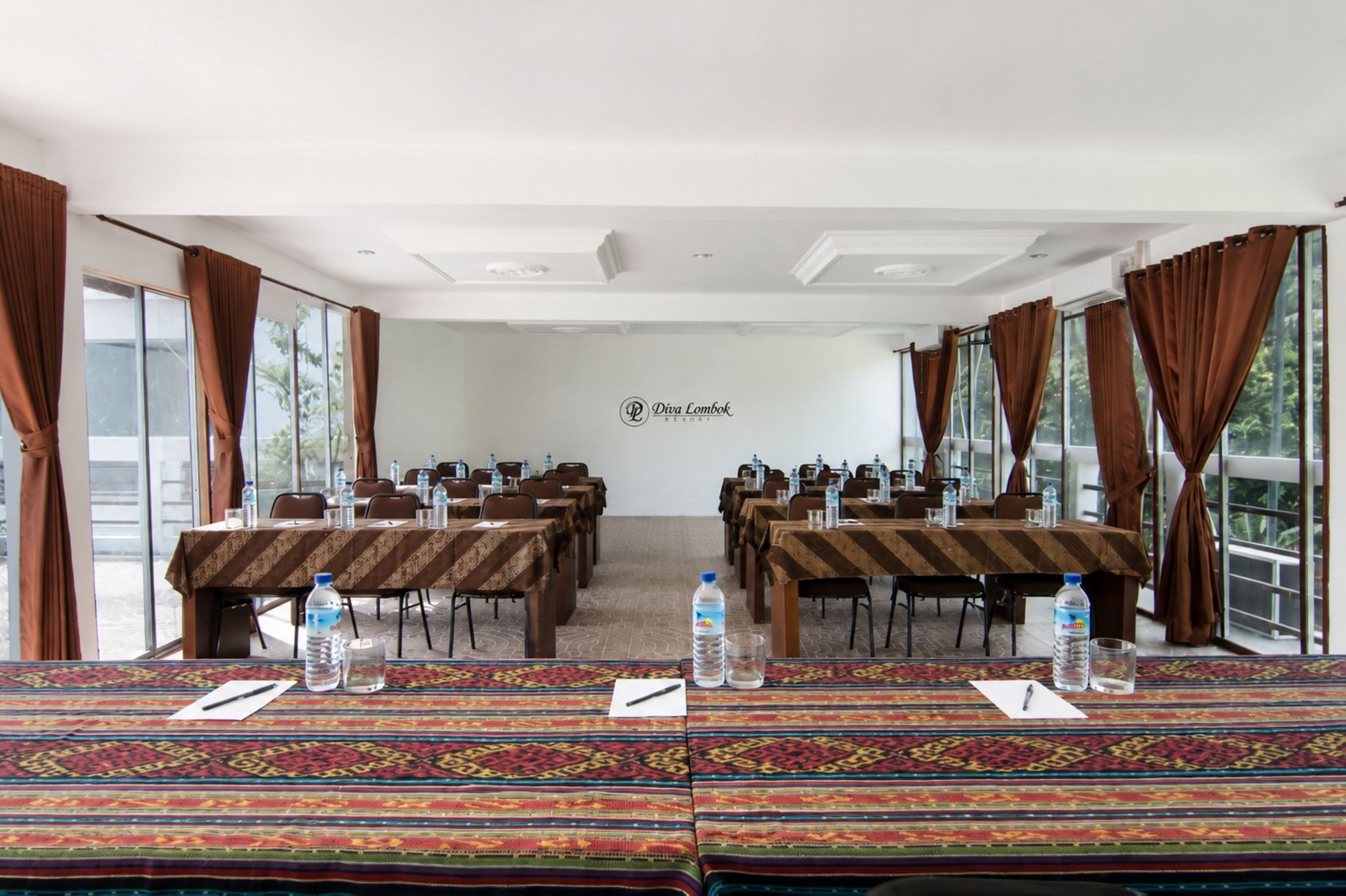 A conference room with tables, chairs, water bottles, and a logo on the wall.