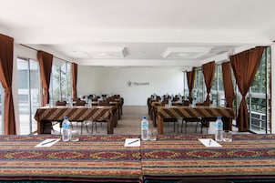 Una sala conferenze con tavoli, sedie, bottiglie d'acqua e un logo sul muro.