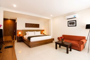 Une chambre d’hôtel équipée d’un lit, d’un canapé, d’une petite table, d’une télévision et d’un appareil de climatisation.