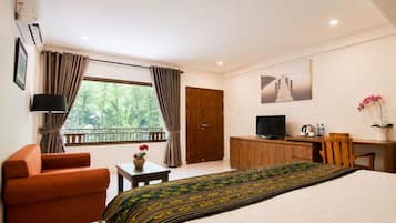 A hotel room with a bed, a desk, a television, a chair, and a window with curtains.