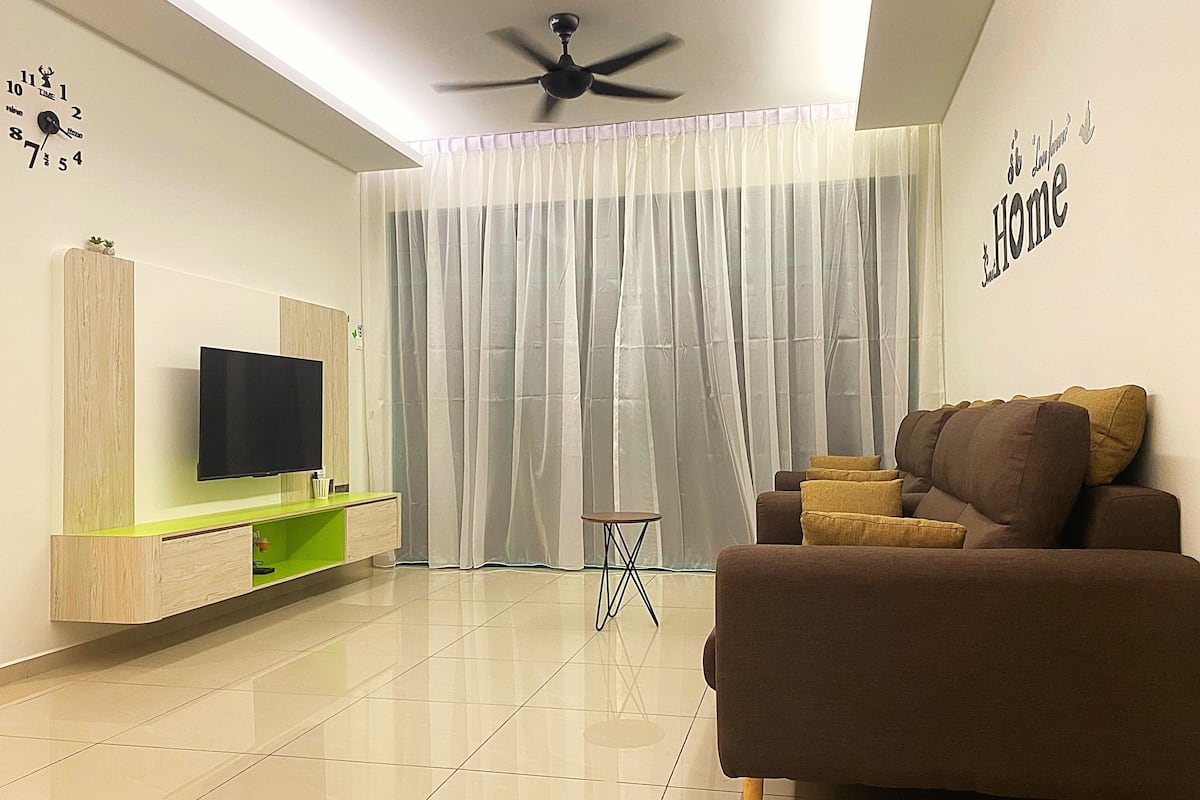 A modern living room with a flat-screen TV, a brown sofa, and a green console table.
