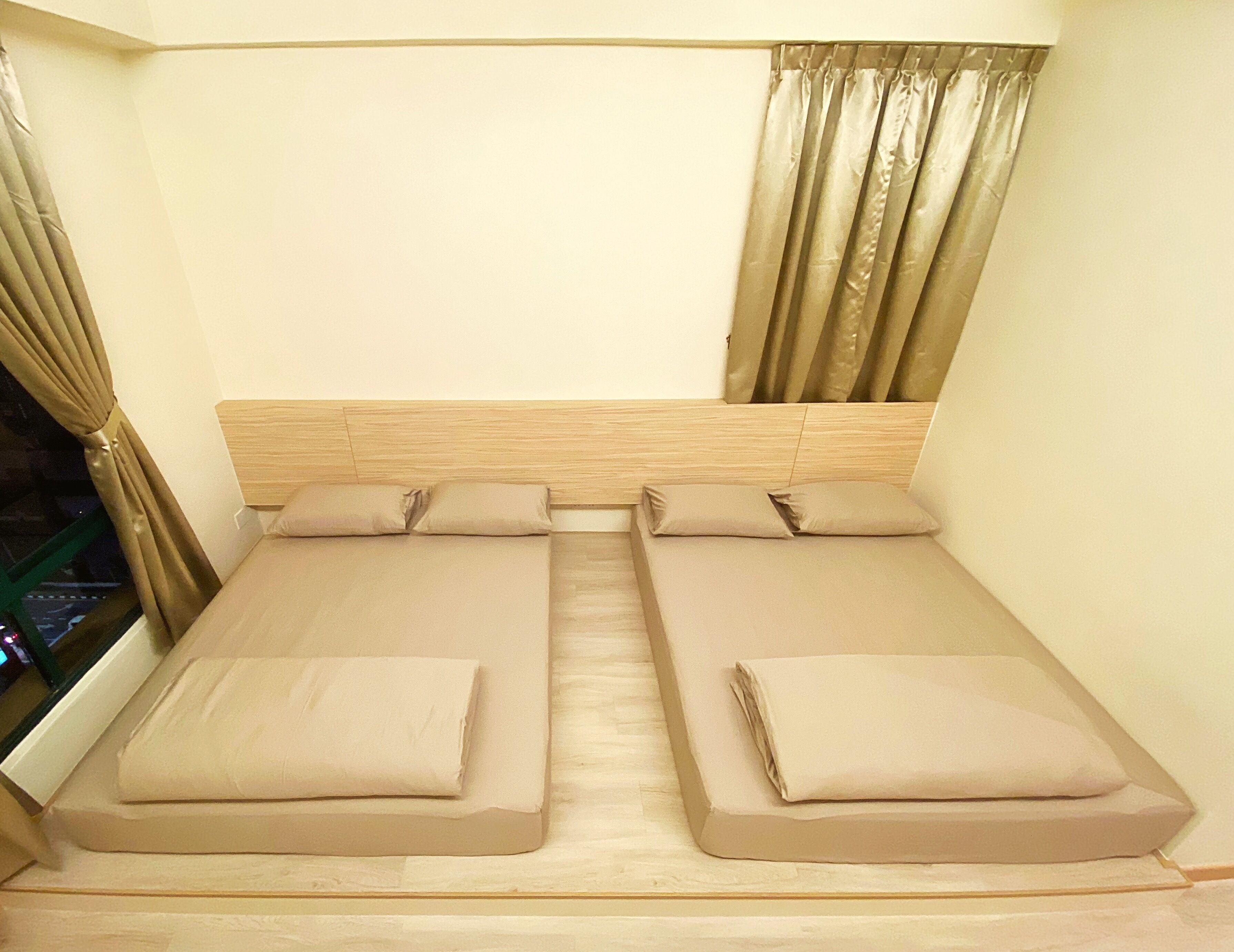 A twin bed room with a wooden headboard, beige bedding, and a window with curtains.