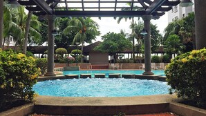 A pool area with a pergola structure, palm trees, and lounge chairs. - Amadel Residence (Malacca City)