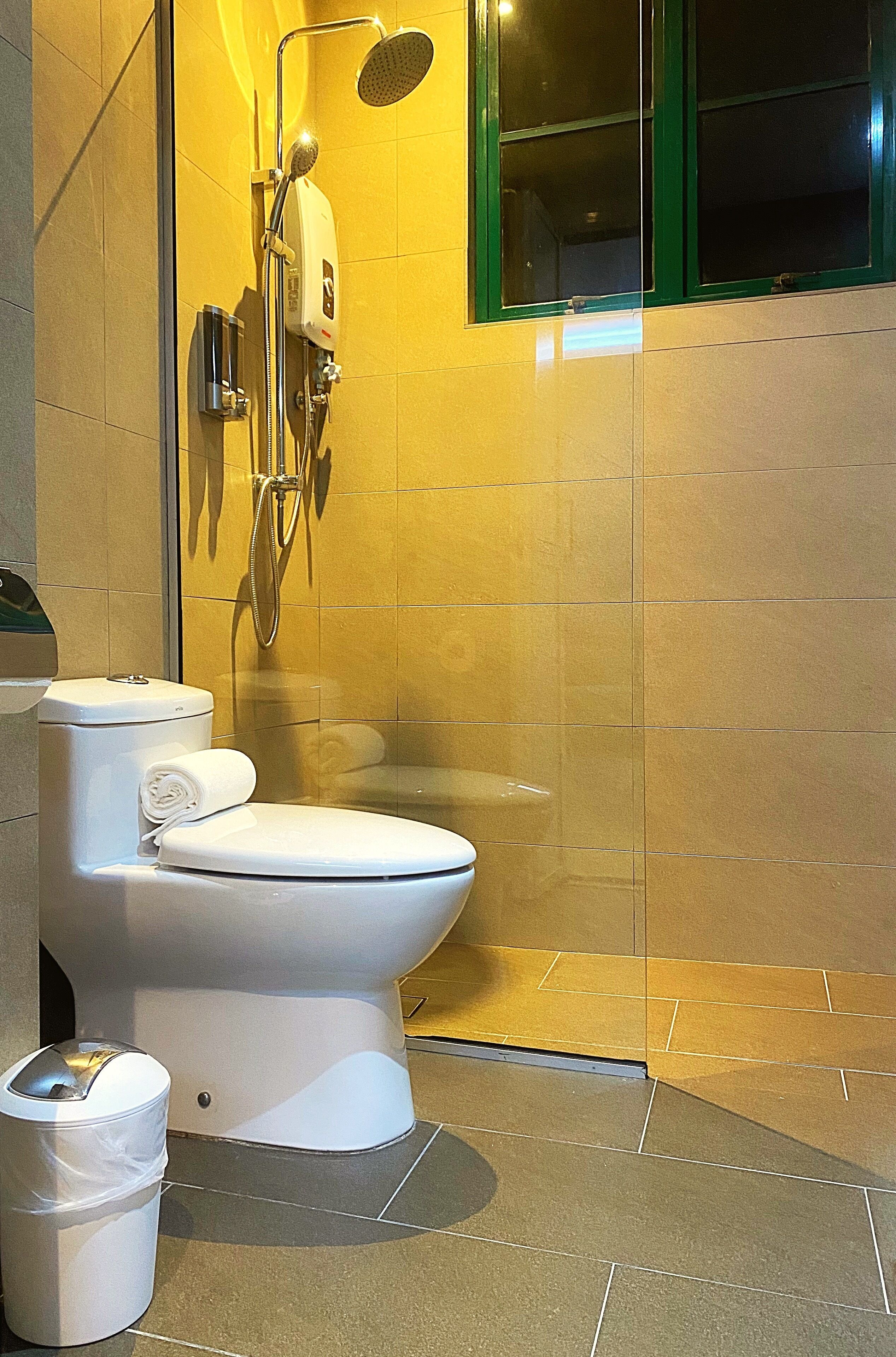 Een moderne badkamer met toilet, douche en een raam met glas.