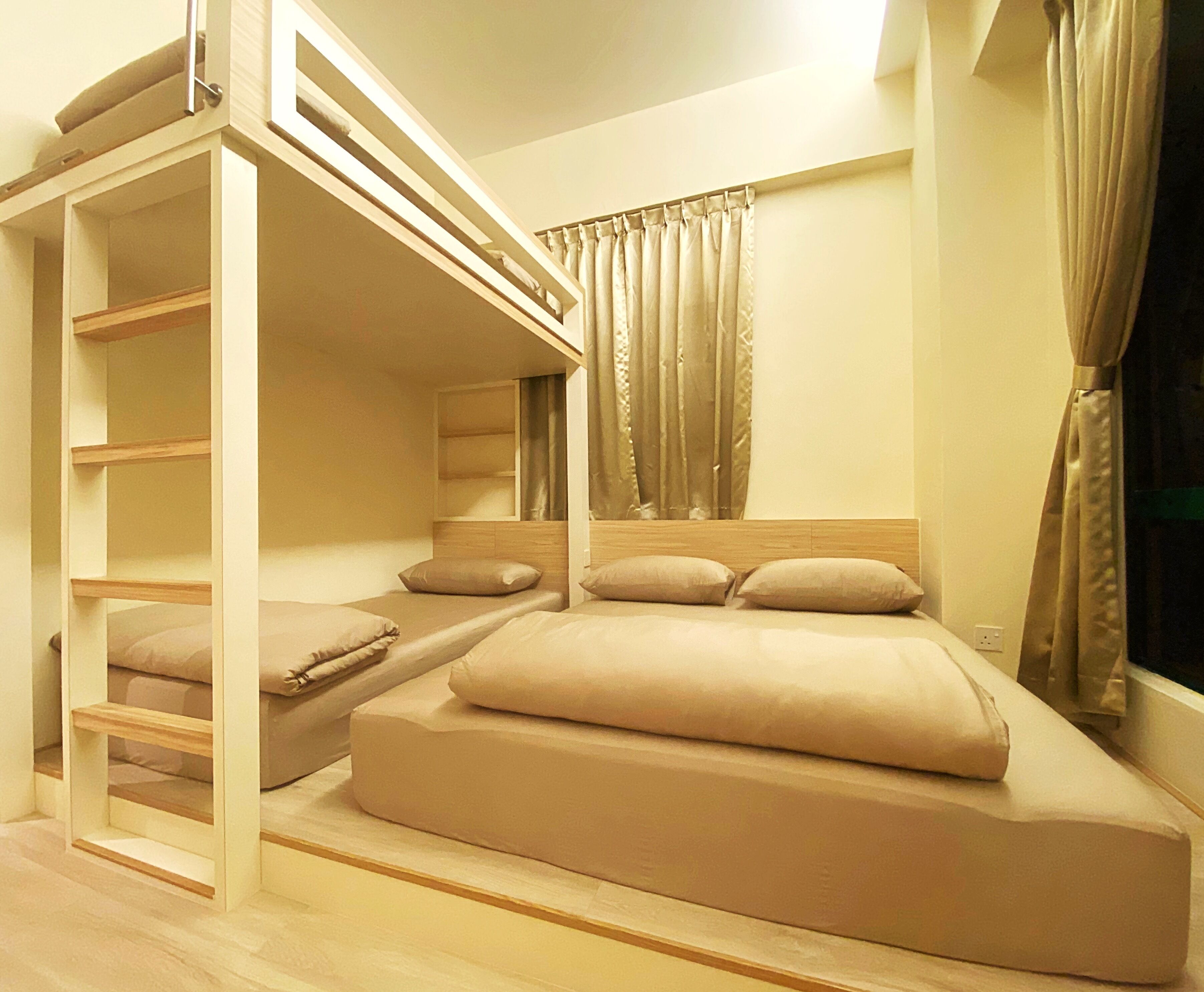 A bunk bed room with a wooden ladder, a headboard, and a window with curtains.