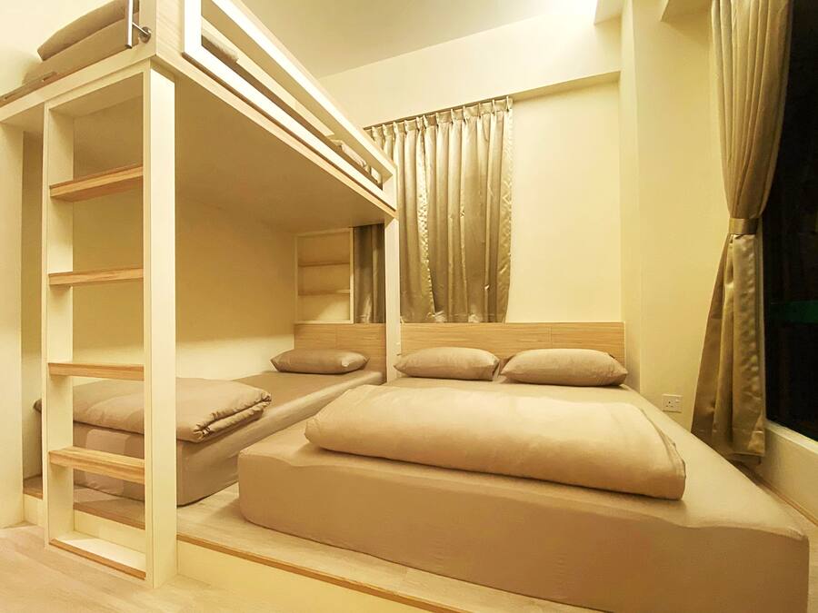 Habitación con literas, una escalera de madera, cabecero y ventana con cortinas.