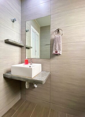 A modern bathroom with a white sink, a mirror, and a towel hanging on a hook.
