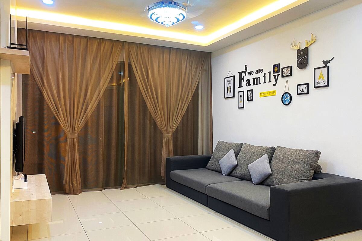 A living room with a sofa, curtains, a ceiling fan, and wall decorations.