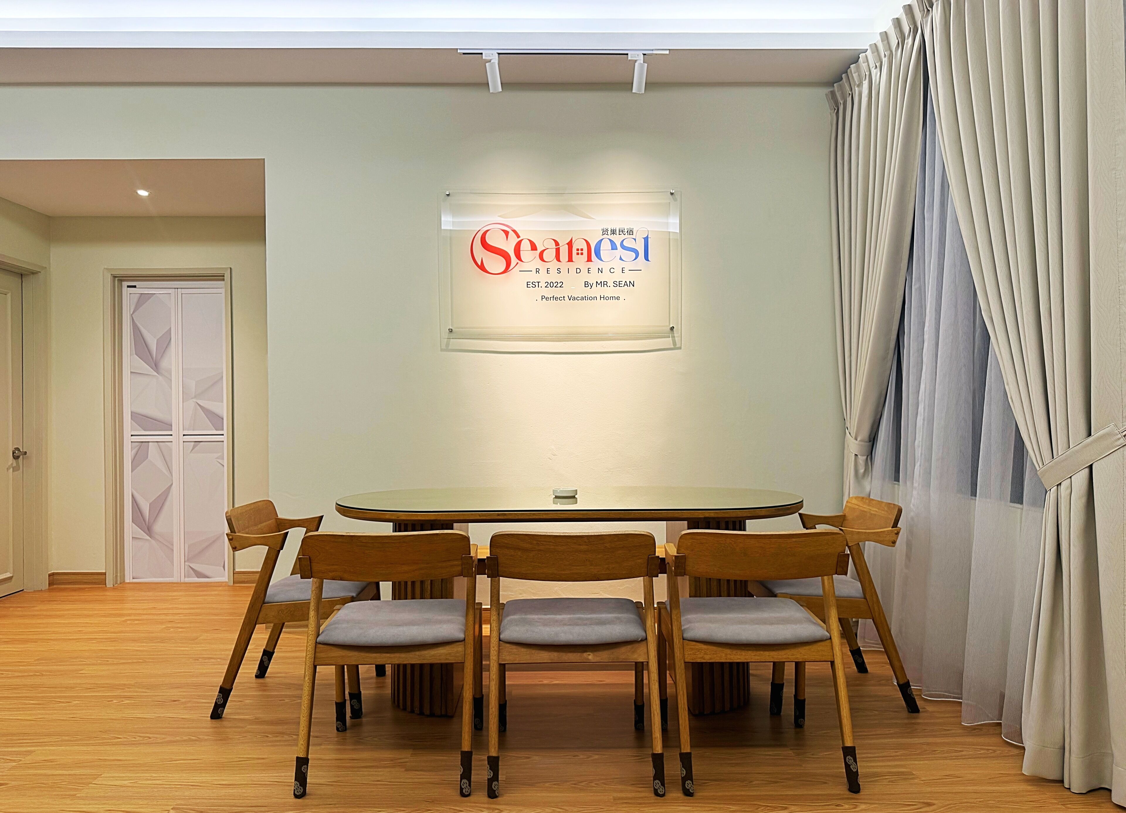 A conference room with a round table, six wooden chairs, and a sign on the wall.