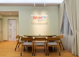 A conference room with a round table, six wooden chairs, and a sign on the wall.