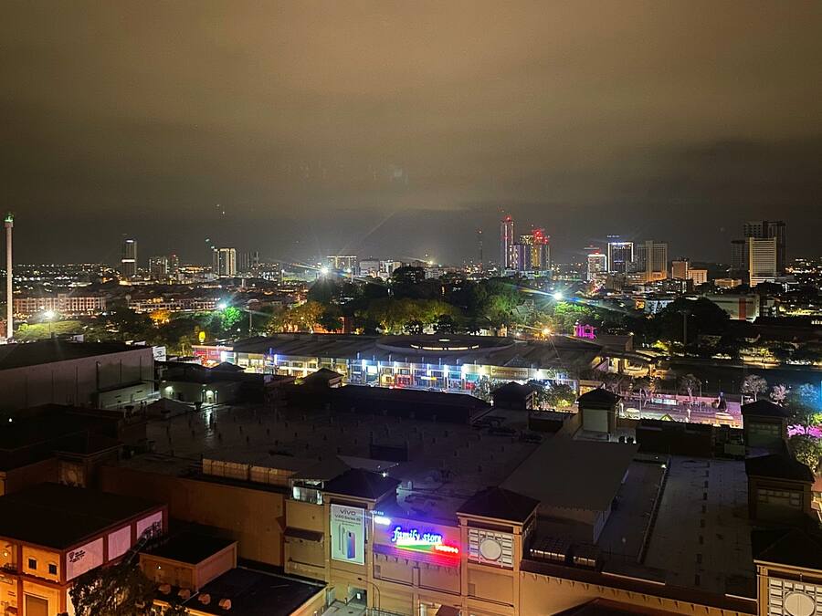 Un paisaje urbano nocturno con edificios iluminados y una destacada torre del reloj.