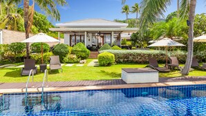 A pool area with a clear view of the pool, lounge chairs, and a building with a covered patio. - Lotus Samui (Koh Samui)
