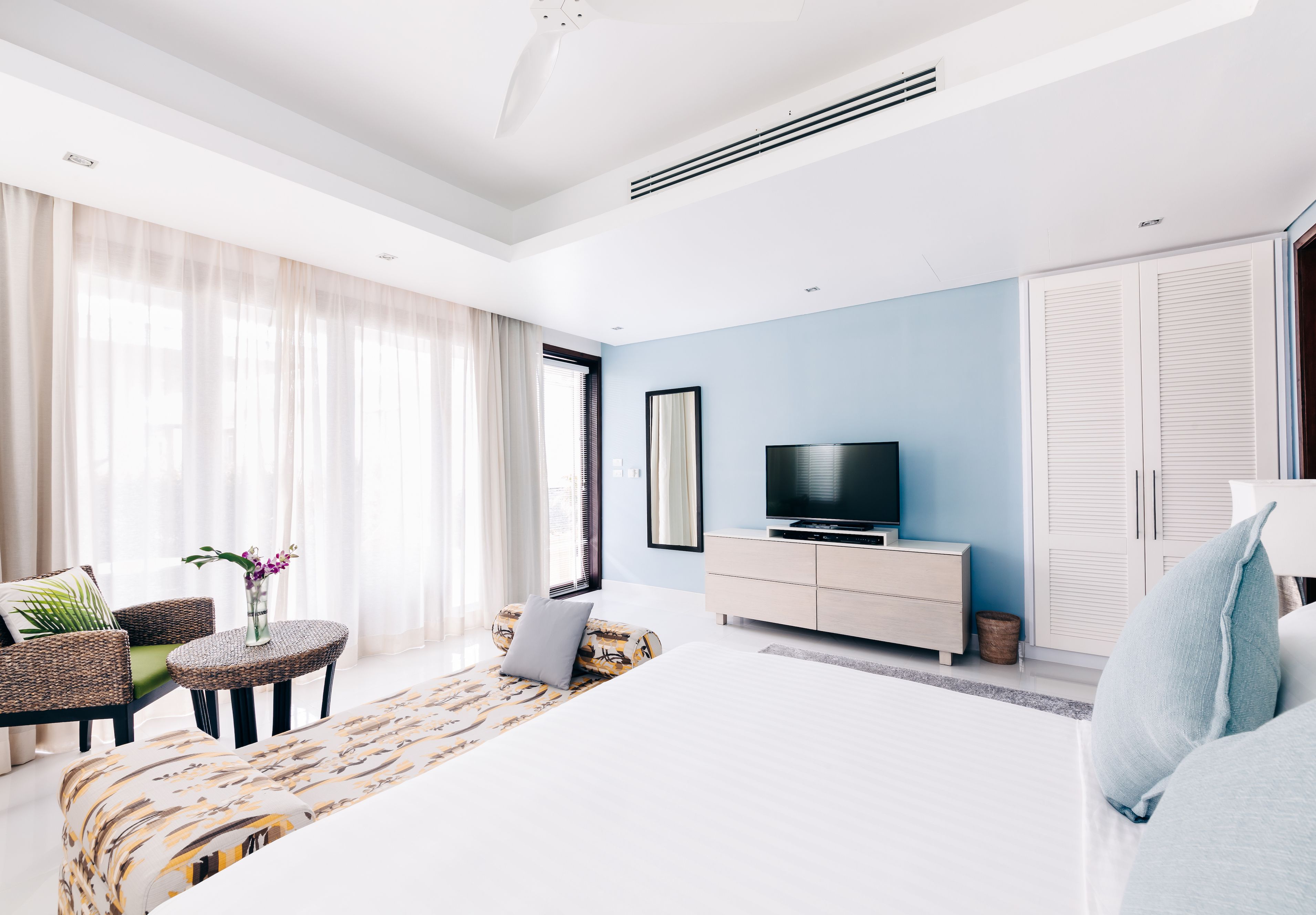Ein modernes Hotelzimmer mit einem großen Bett, einer Couch, einem Fernseher und einem Kleiderschrank.
