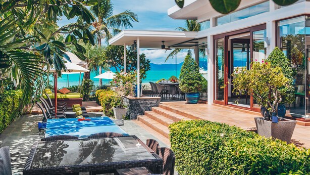 A modern outdoor patio with a pool, lounge chairs, and a view of the ocean. - Lotus Samui (Koh Samui)