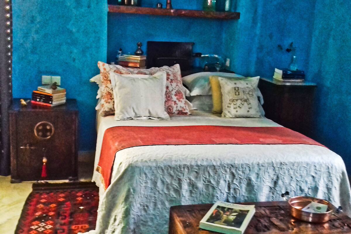 Une chambre à coucher comprenant un lit, une table de chevet, une armoire en bois et un tapis à motifs.