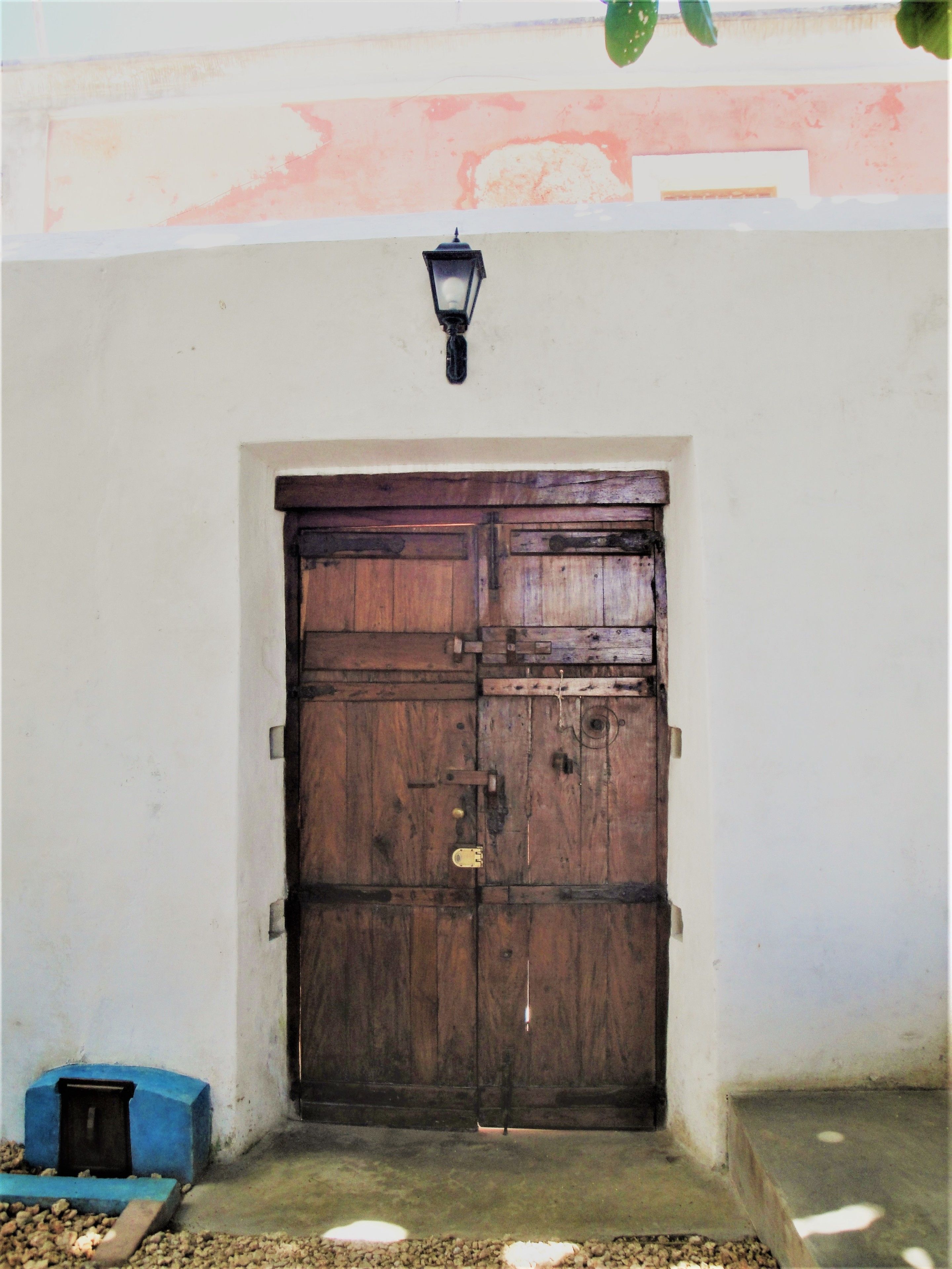 A large wooden door with a metal latch and a small metal box beside it.