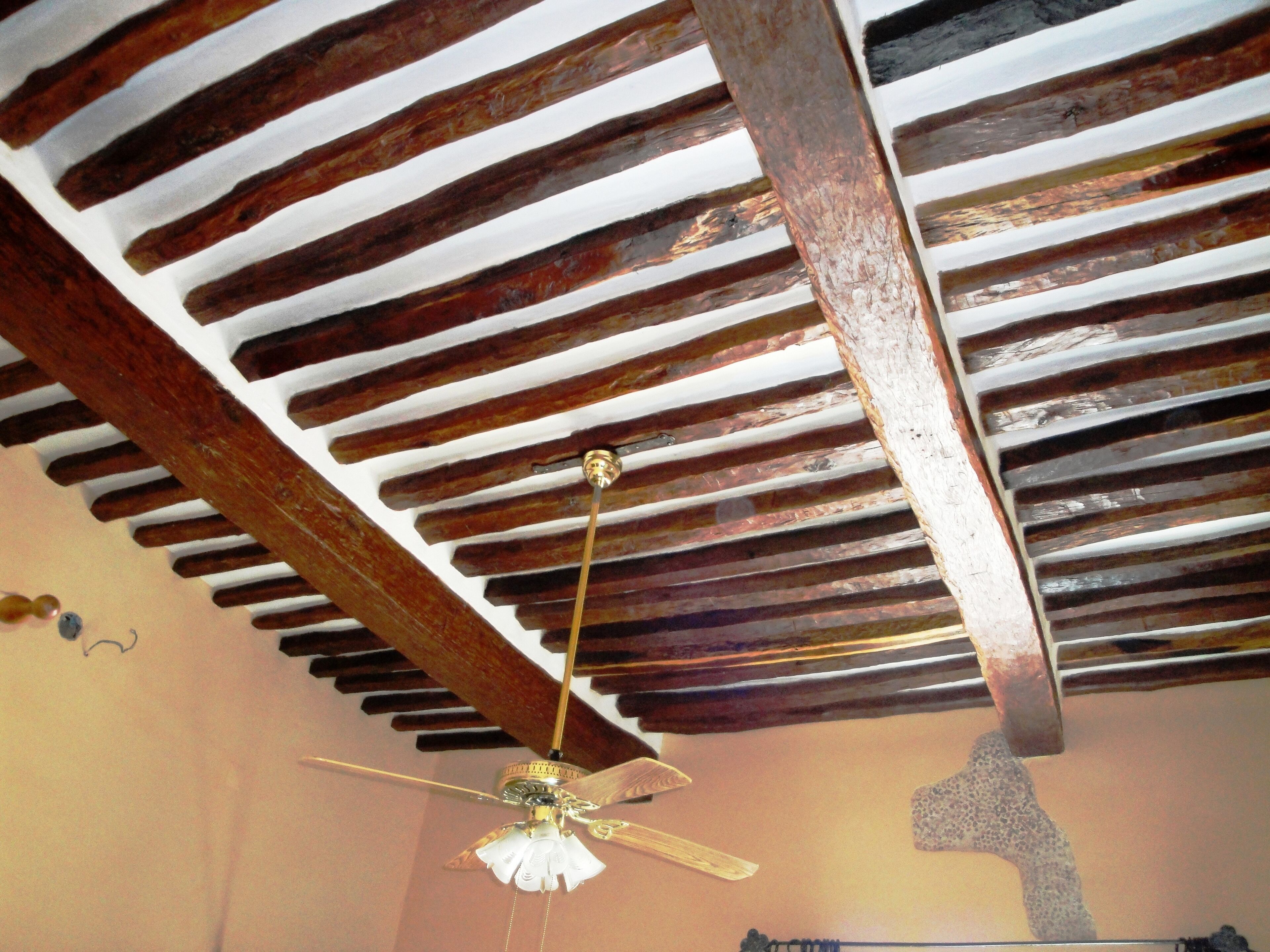 A ceiling with exposed wooden beams and a ceiling fan.