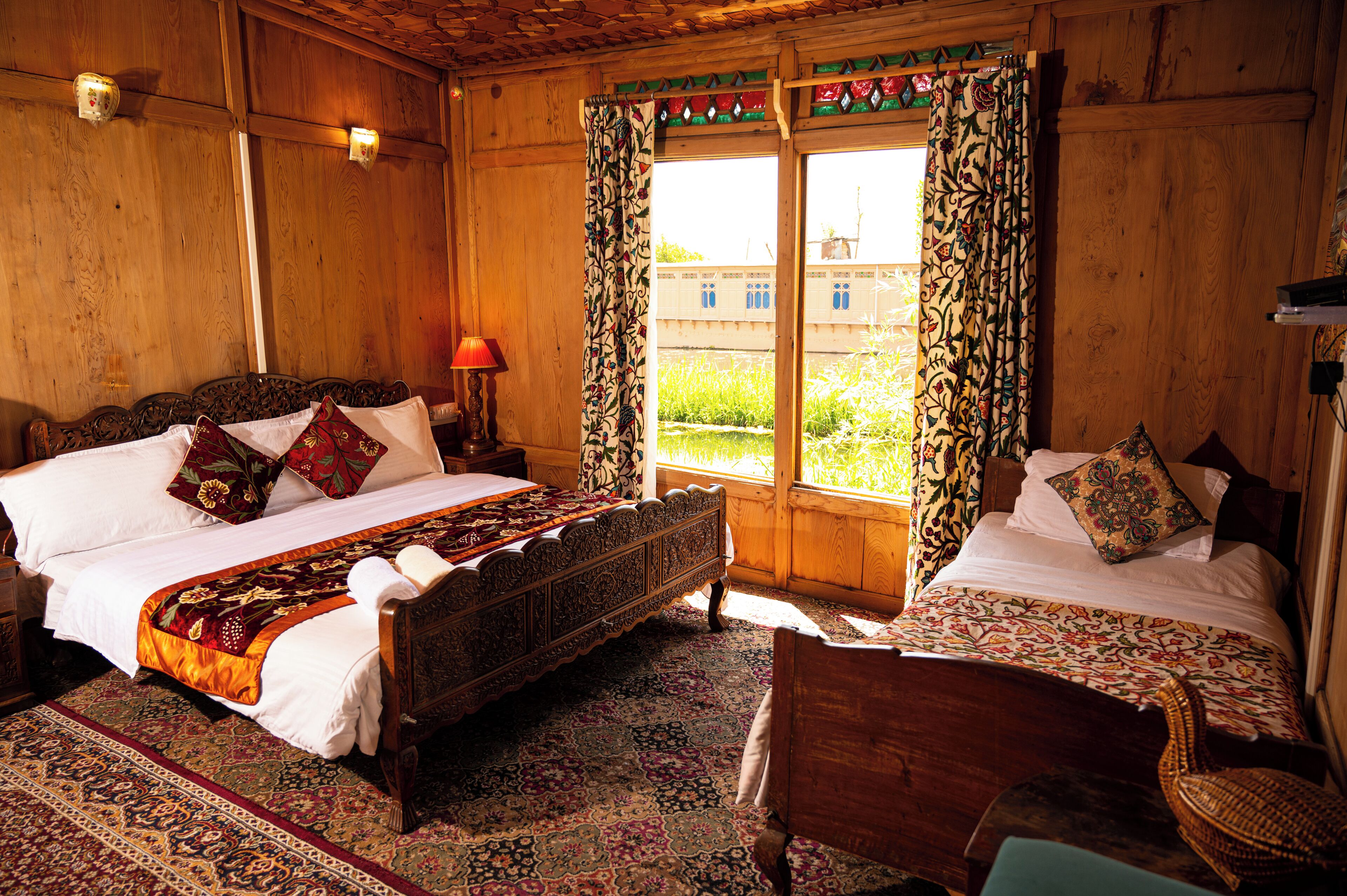 A traditional wooden room with a large bed, a smaller bed, and a chair.