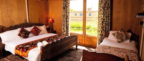 A traditional wooden room with a large bed, a smaller bed, and a chair.