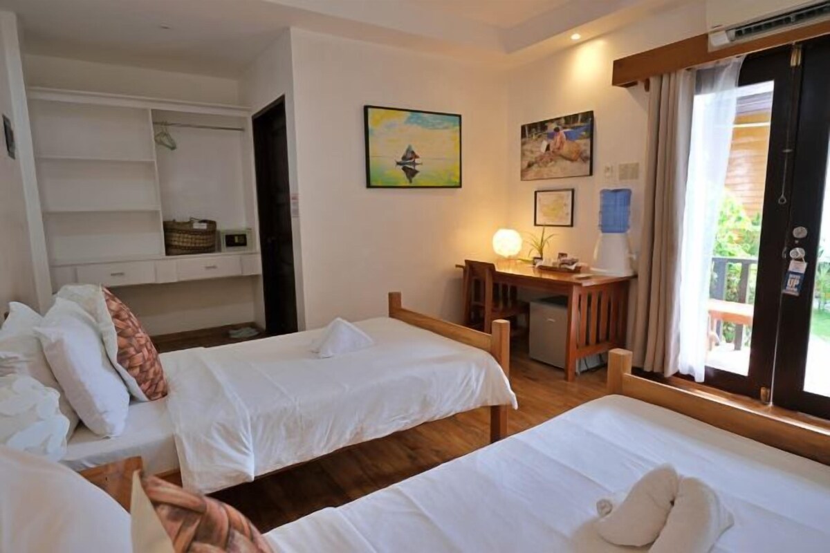 Habitación de hotel con dos camas, un escritorio y un balcón.