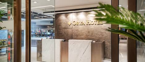 Un comptoir d’accueil avec un plateau en marbre et une enseigne indiquant « ORYA HOTEL ».