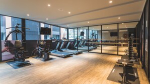 A modern gym with treadmills, weight machines, and a large mirror wall. - Royal Rose Hotel Xinsheng (Taipei)