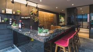 A modern kitchen with a marble countertop, bar stools, and a wooden wall. - Royal Rose Hotel Xinsheng (Taipei)