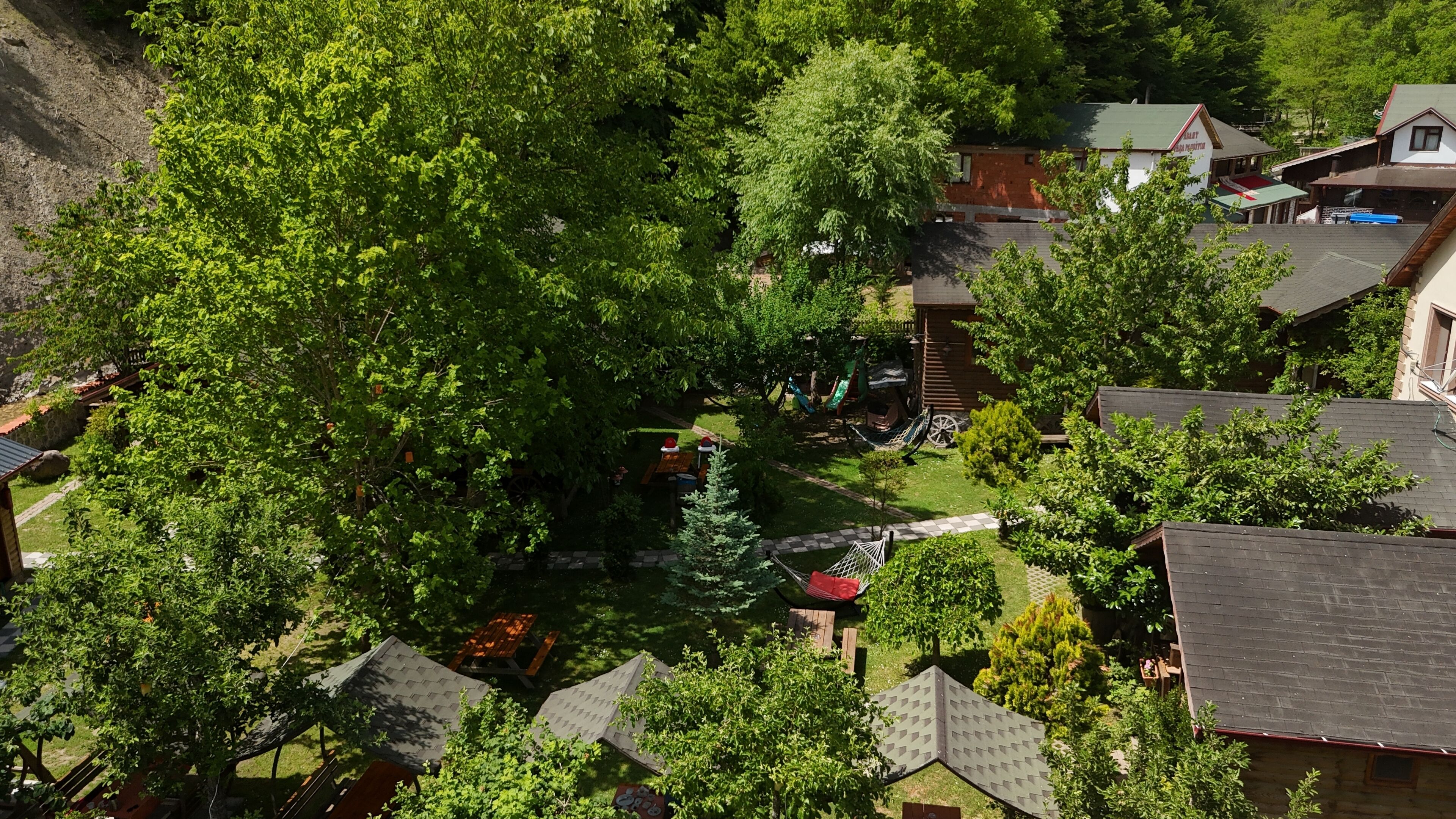 A residential area with multiple houses, a playground, and a large tree in the foreground.