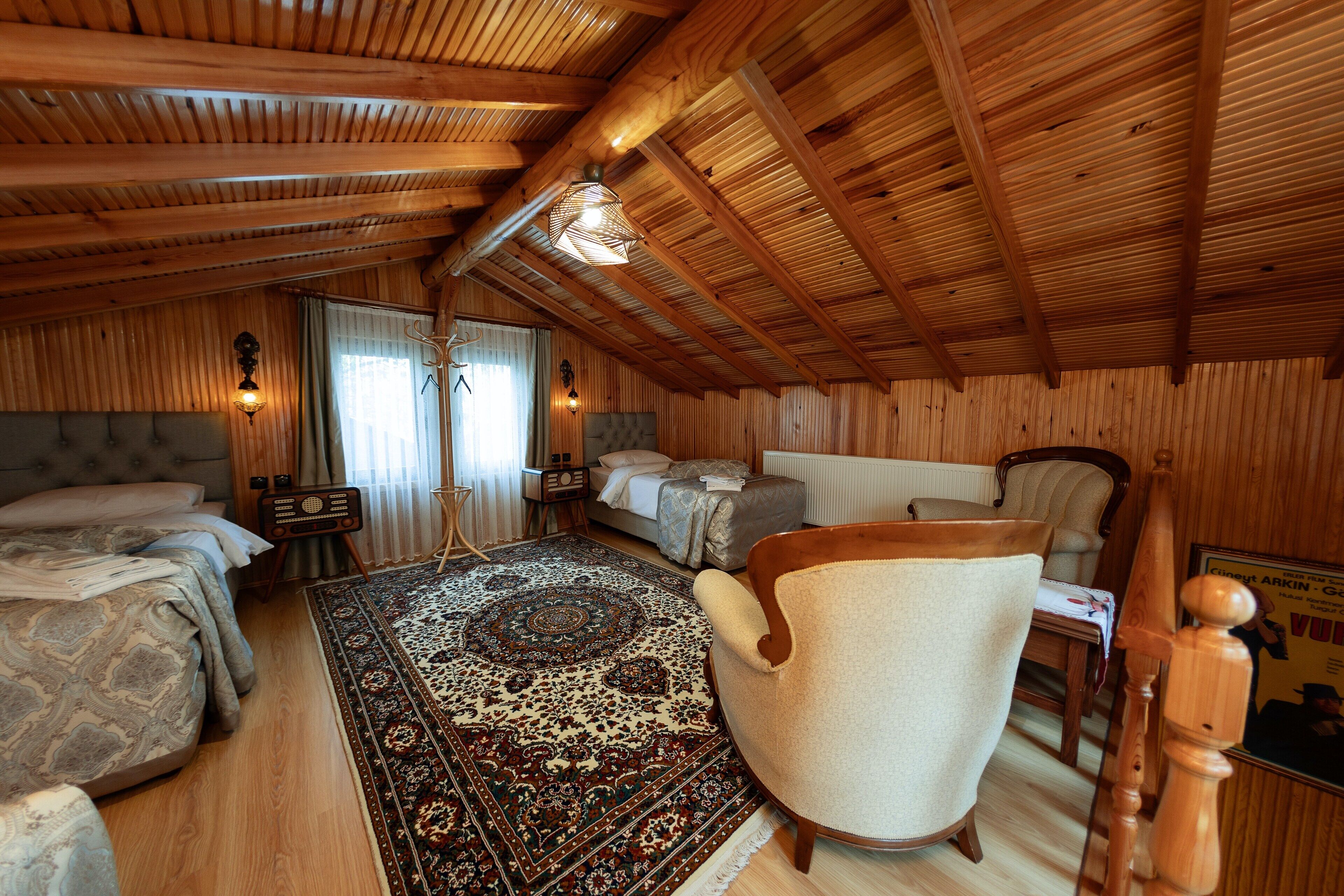 Un dormitorio acogedor, con muebles de madera, una cama grande, una silla, una mesita pequeña y un tapete decorativo.