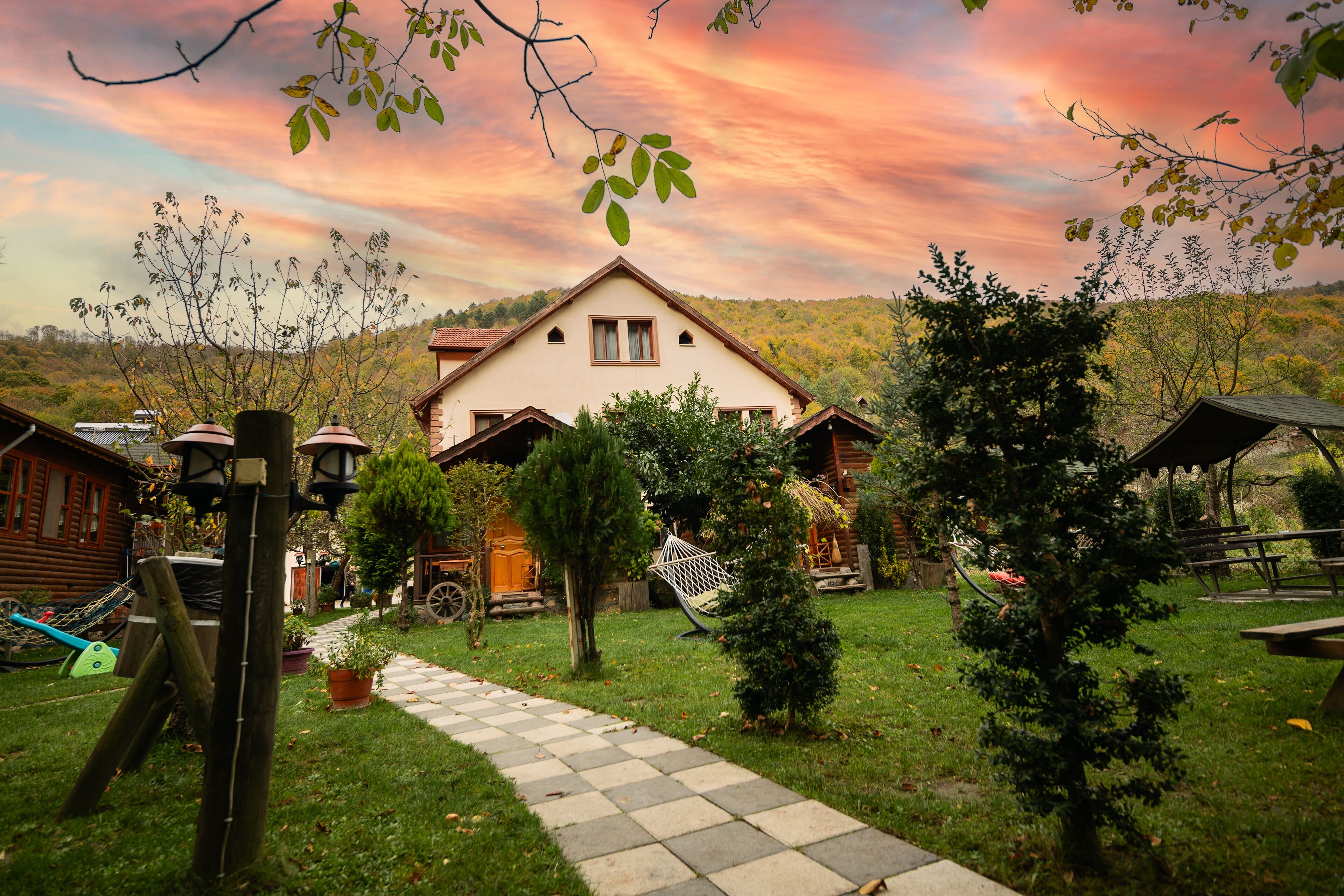 A countryside house with a garden path leading to the entrance, surrounded by trees and a scenic view.